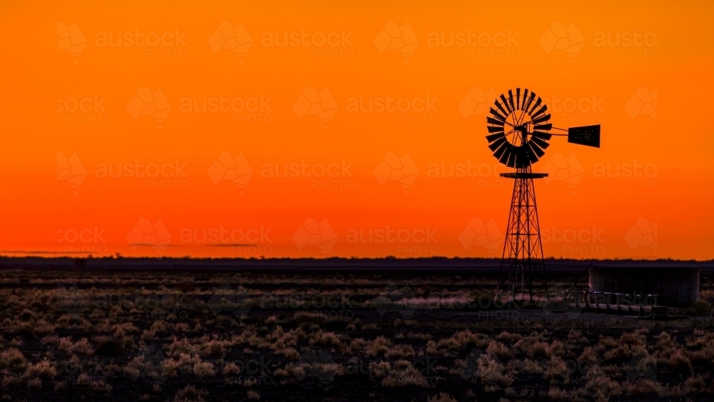 Windmill silhouette against an orange Sunset - Australian Stock Image