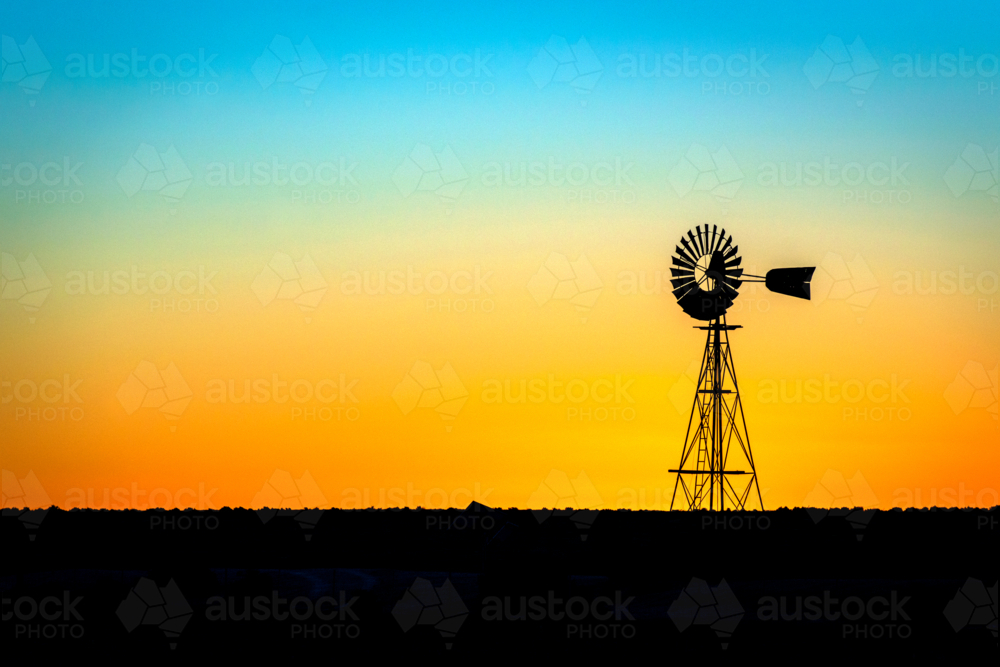Windmill silhouetted against a vivid sunset gradient sky. - Australian Stock Image