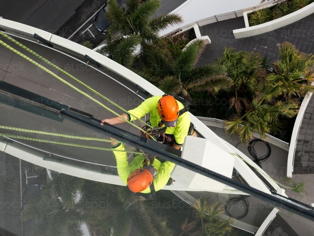 Window cleaner abseiling down a tall building on the Gold Coast - Australian Stock Image