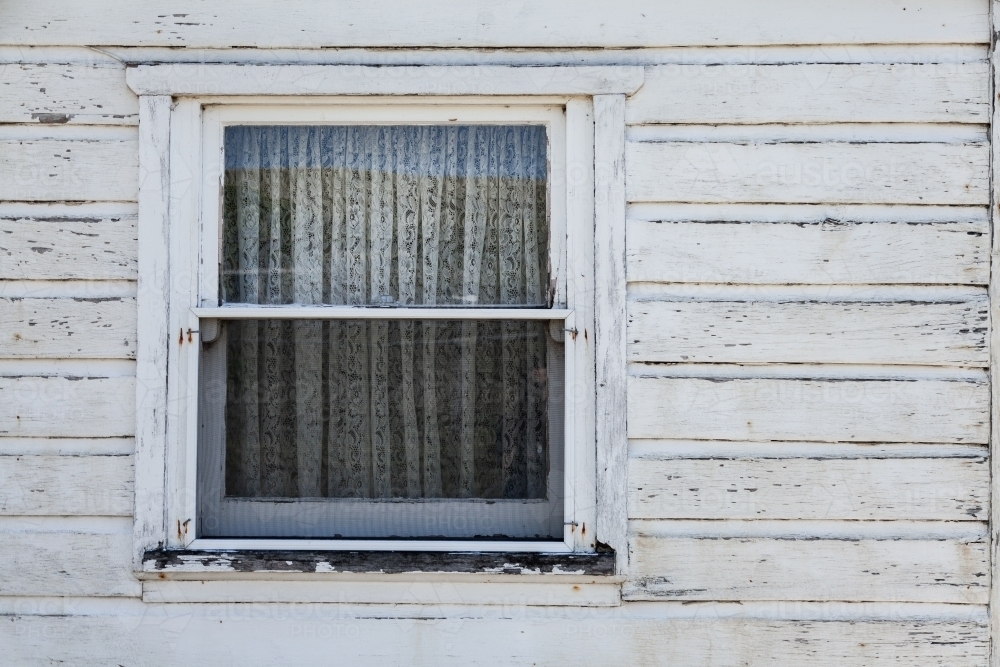Window with white lace curtain on old weatherboard farm building - Australian Stock Image