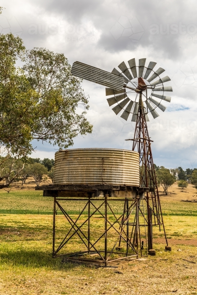 Windpump (windmill) and water tank on a dry farmland property - Australian Stock Image