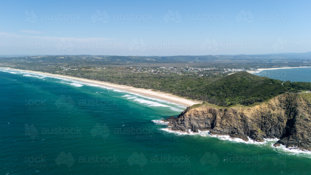Windswept headland above rugged coastline with steep cliffs with long stretch of white sand beach - Australian Stock Image