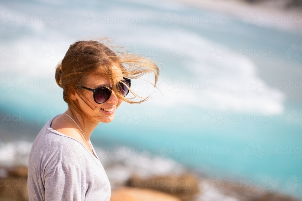 Windswept young woman at beach with hair blowing in the wind - Australian Stock Image