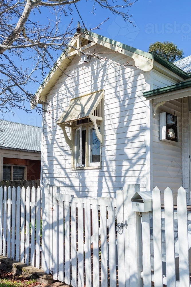 winter tree shadows on white weatherboard house - Australian Stock Image