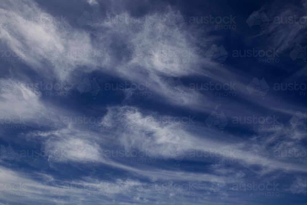 Wispy white clouds against a dark blue sky - Australian Stock Image