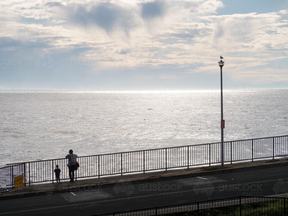 Woman and child leaning on a rail looking out to sea - Australian Stock Image