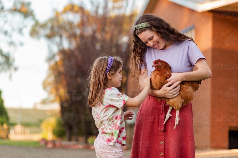 Woman and child with pet hen on farm - Australian Stock Image