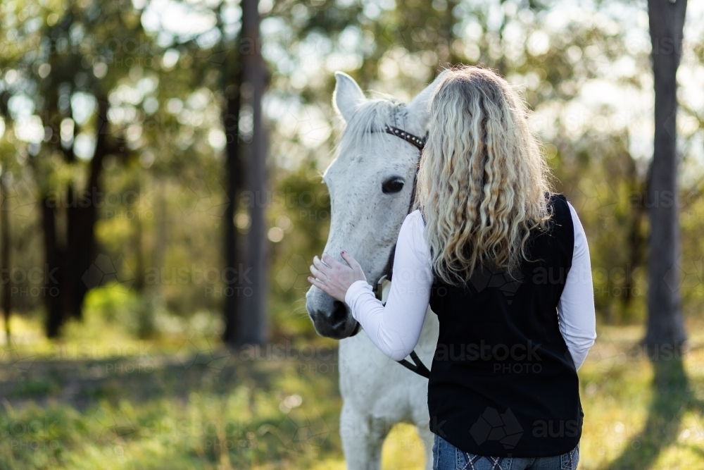 Woman and her horse in bushland with bokeh background - Australian Stock Image