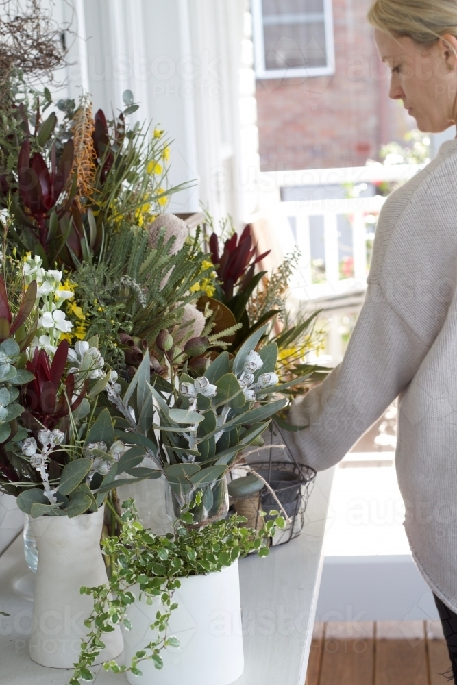 Woman arranging flowers on table - Australian Stock Image