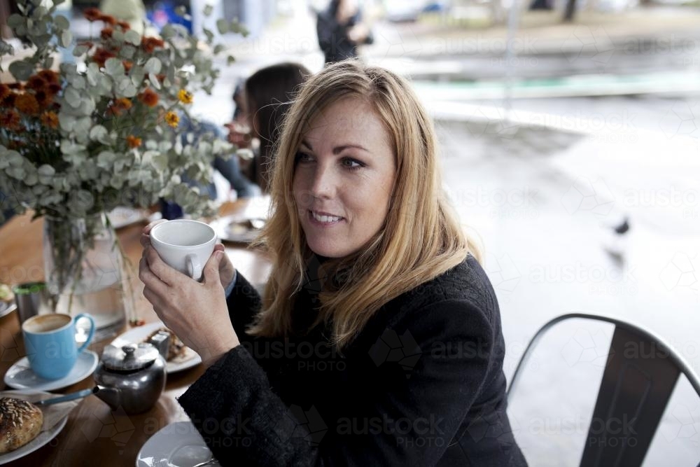 Woman at cafe drinking out of mug - Australian Stock Image