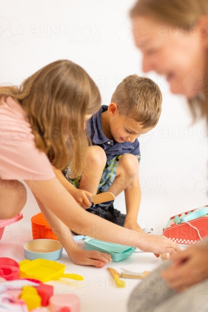 woman blurred in foreground with children playing with toys behind her - Australian Stock Image
