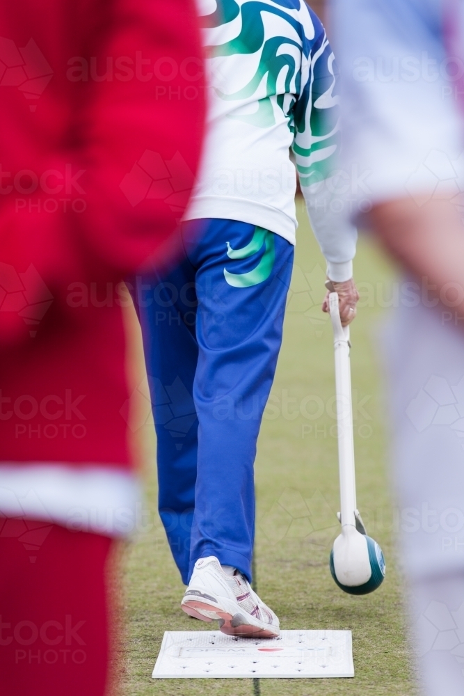 Woman bowling a lawn bowl with a bowlers arm - Australian Stock Image