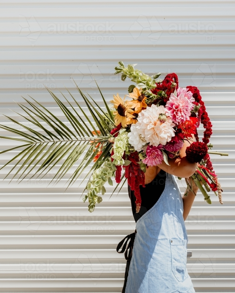 Woman carries big bunch of fresh florals. - Australian Stock Image