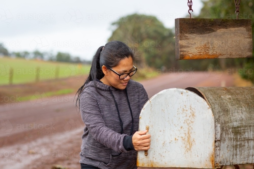 Woman collecting mail from roadside mailbox - Australian Stock Image