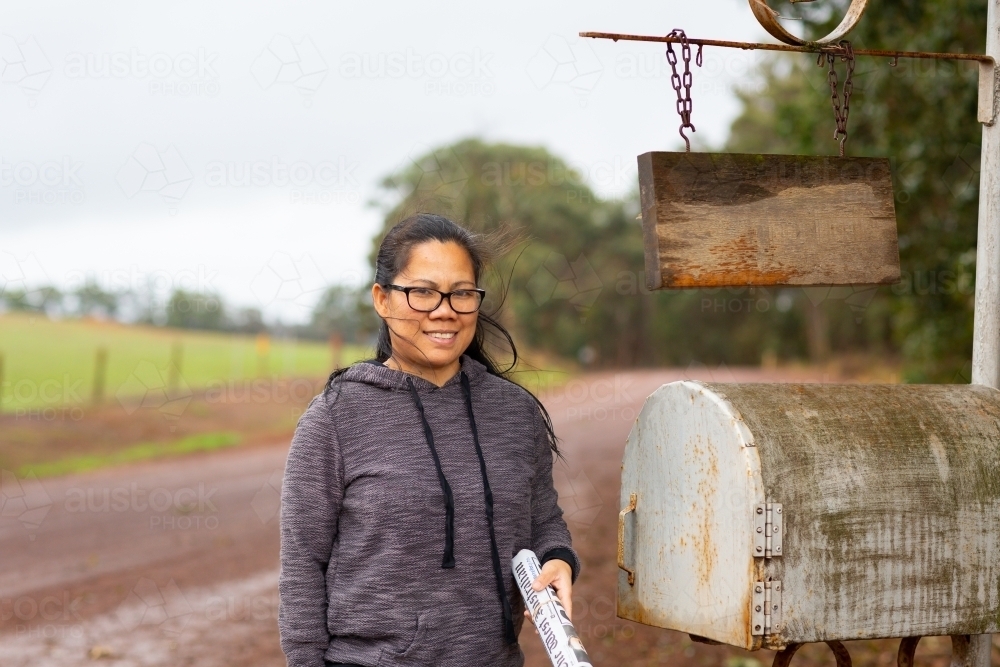 Woman collecting mail from roadside mailbox - Australian Stock Image