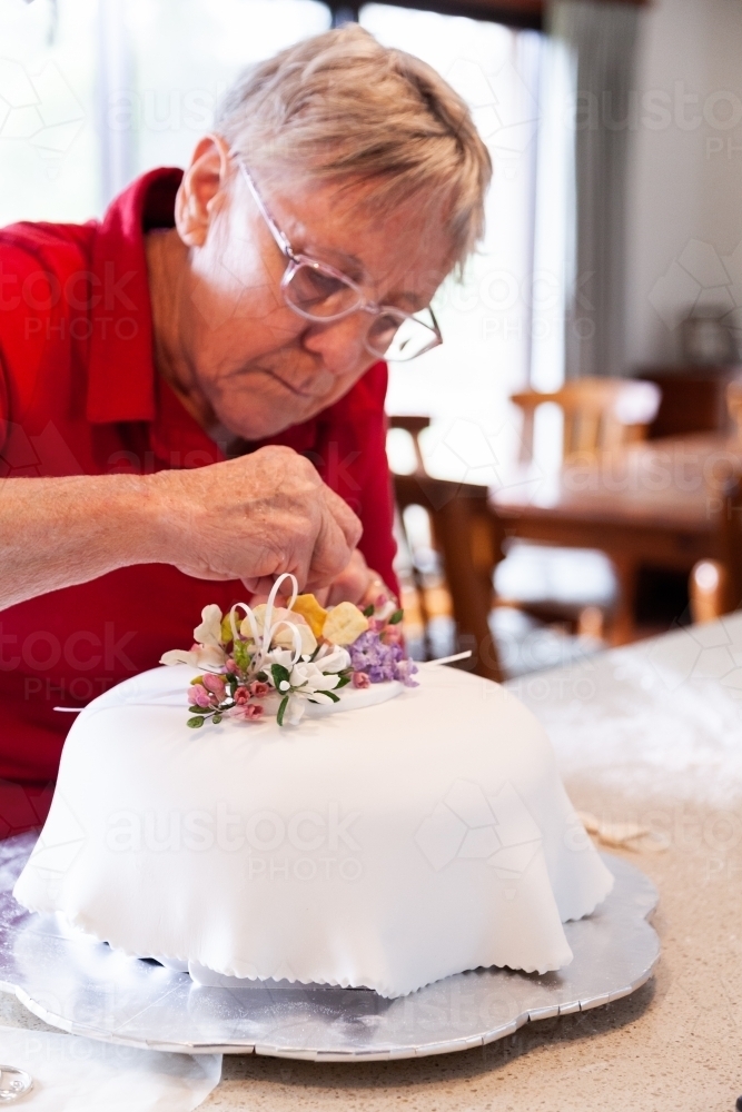 Woman decorating birthday cake with hand made native flower cake topper - Australian Stock Image