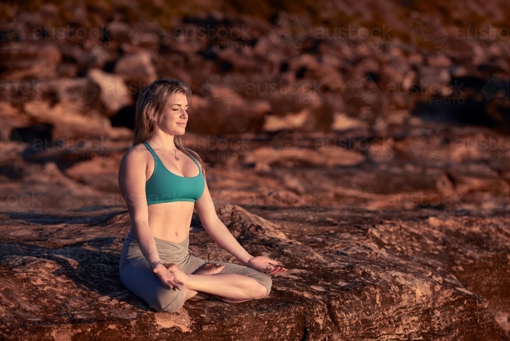 Woman doing yoga by the ocean - Australian Stock Image