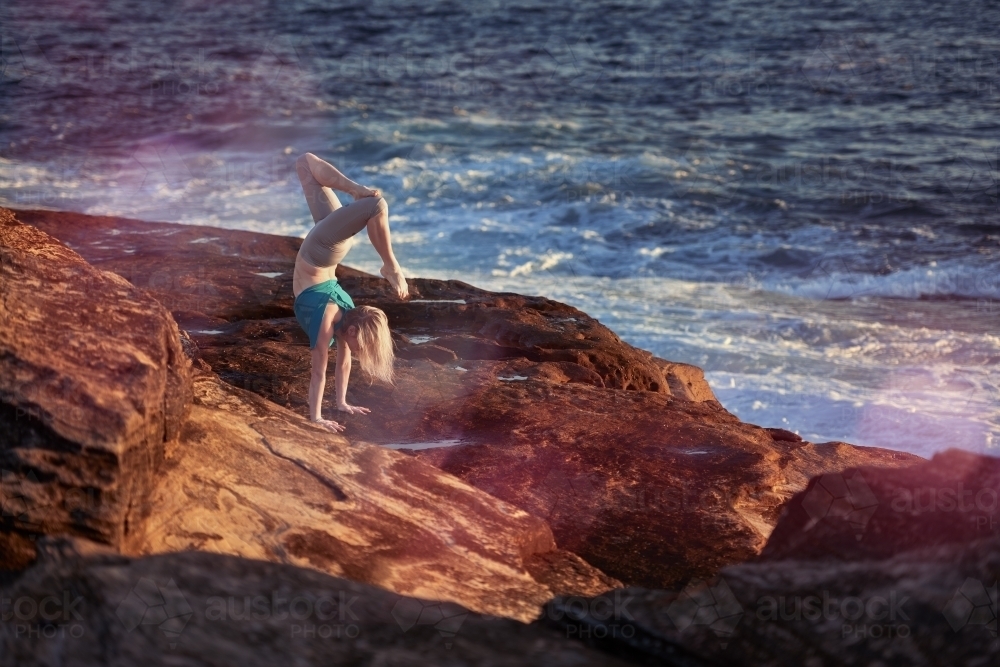 Woman doing yoga by the ocean - Australian Stock Image