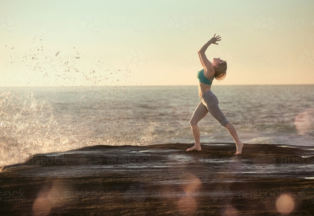 Woman doing yoga by the ocean - Australian Stock Image