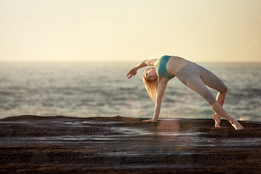 Woman doing yoga by the ocean - Australian Stock Image