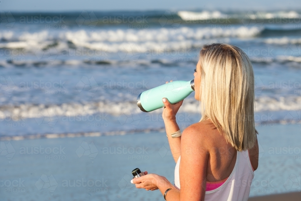 woman drinking from a water bottle after a workout - Australian Stock Image