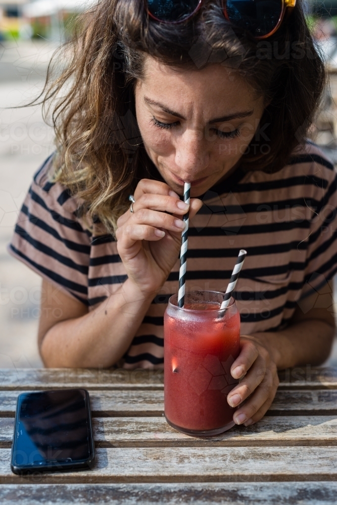 woman drinking fruit drink in a cafe - Australian Stock Image