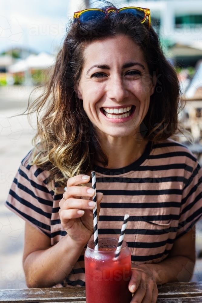 woman drinking fruit drink in a cafe - Australian Stock Image