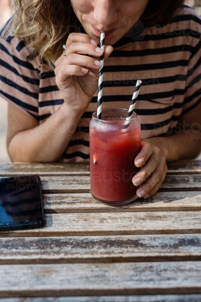 woman drinking fruit drink in a cafe - Australian Stock Image
