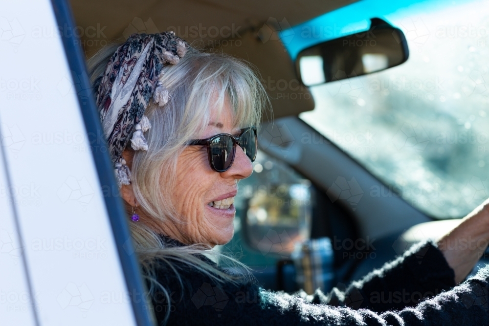 woman driving a vehicle seen through car window - Australian Stock Image