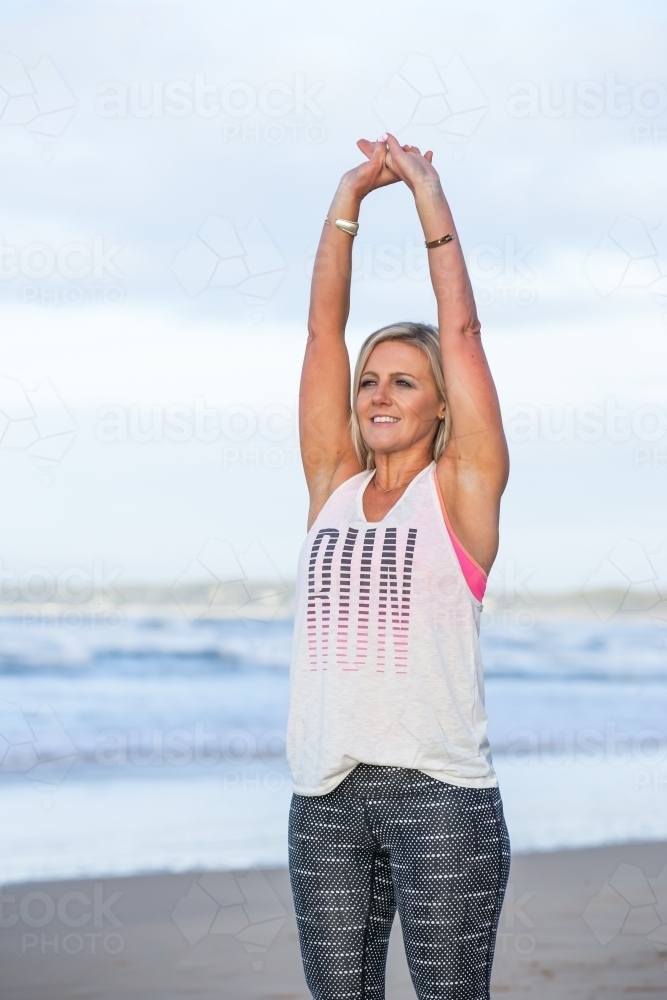 Woman exercising and stretching at the beach - Australian Stock Image