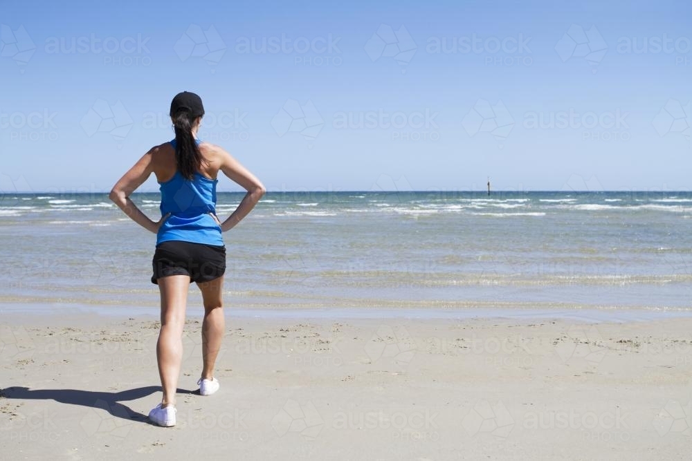 Woman exercising on the beach facing the sea - Australian Stock Image