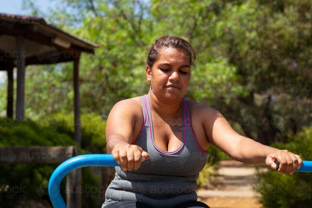 woman exercising outdoors on community fitness equipment - Australian Stock Image