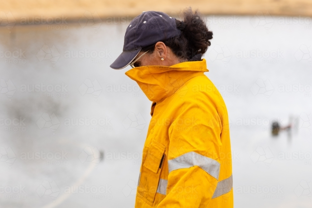 Woman firefighter with face covered by uniform looking down - Australian Stock Image