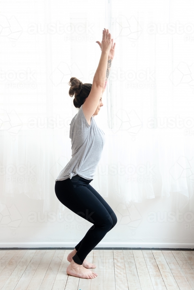 woman full length chair yoga pose in studio - Australian Stock Image