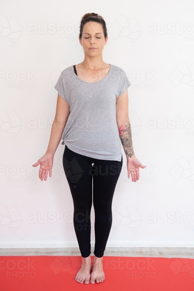 woman full length mountain pose eyes closed yoga on mat in studio - Australian Stock Image