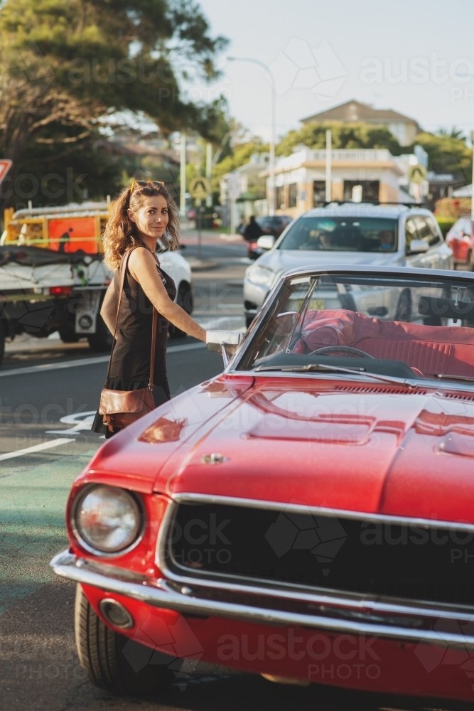 woman getting into classic car parked on the street - Australian Stock Image