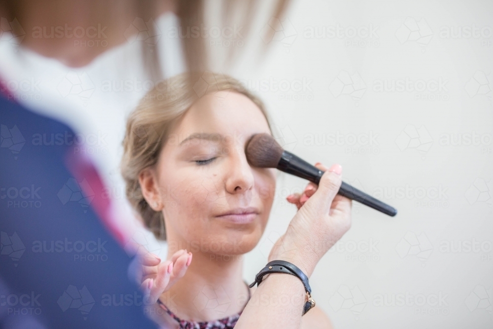 Woman having makeup put on with brush - Australian Stock Image