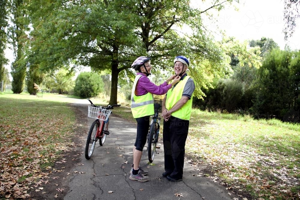Woman helping disabled man with cycling helmet - Australian Stock Image