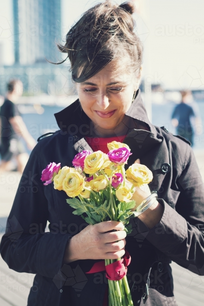 Woman holding a bunch of purple and yellow roses on Docklands promenade - Australian Stock Image