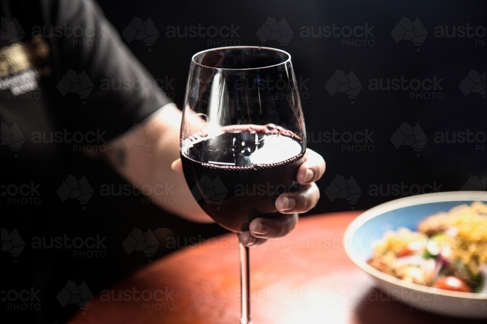 Woman holding a glass of red wine - Australian Stock Image