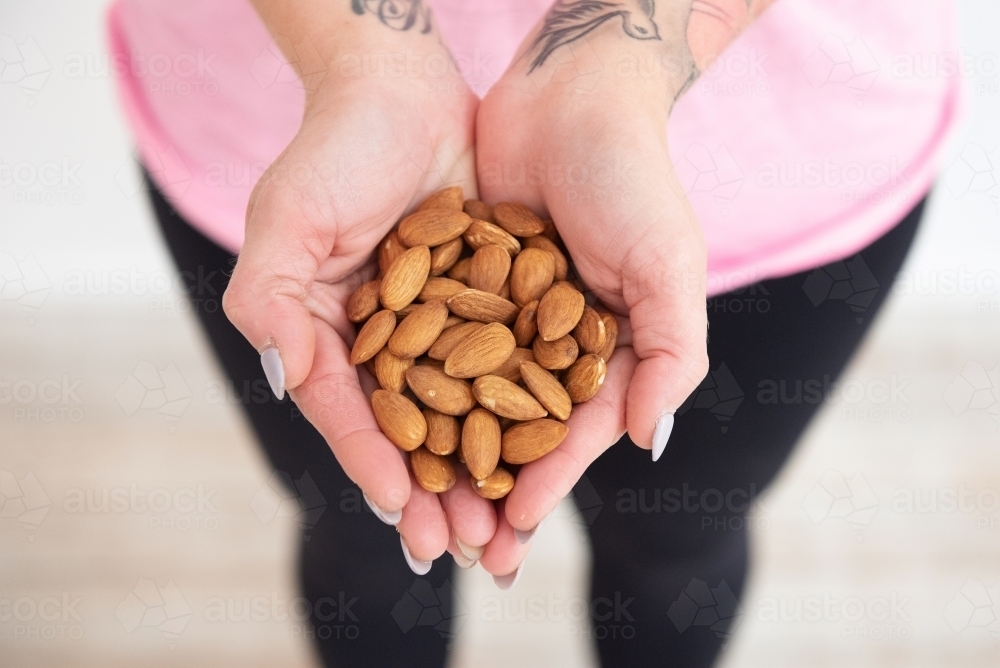 woman holding almonds wearing yoga clothes - Australian Stock Image