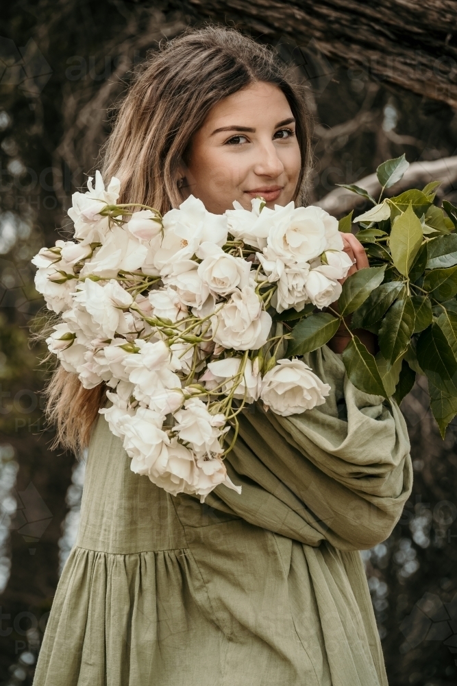 woman holding bunch of roses looking back - Australian Stock Image