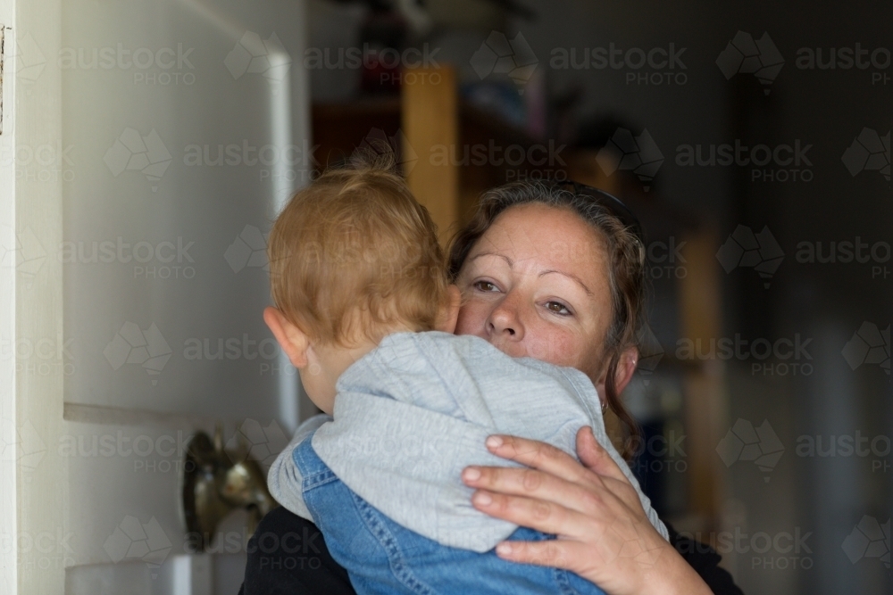 Woman holding child who opening front door - Australian Stock Image