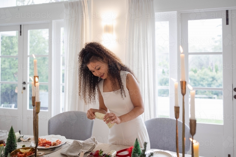Woman holding Christmas bon-bon at table - Australian Stock Image