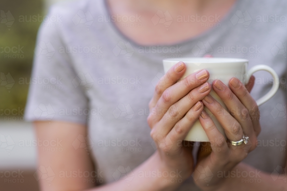 woman holding cup of tea in her hands - Australian Stock Image