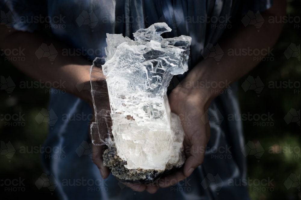 Woman holding, dark, selenite crystal on geode - Australian Stock Image