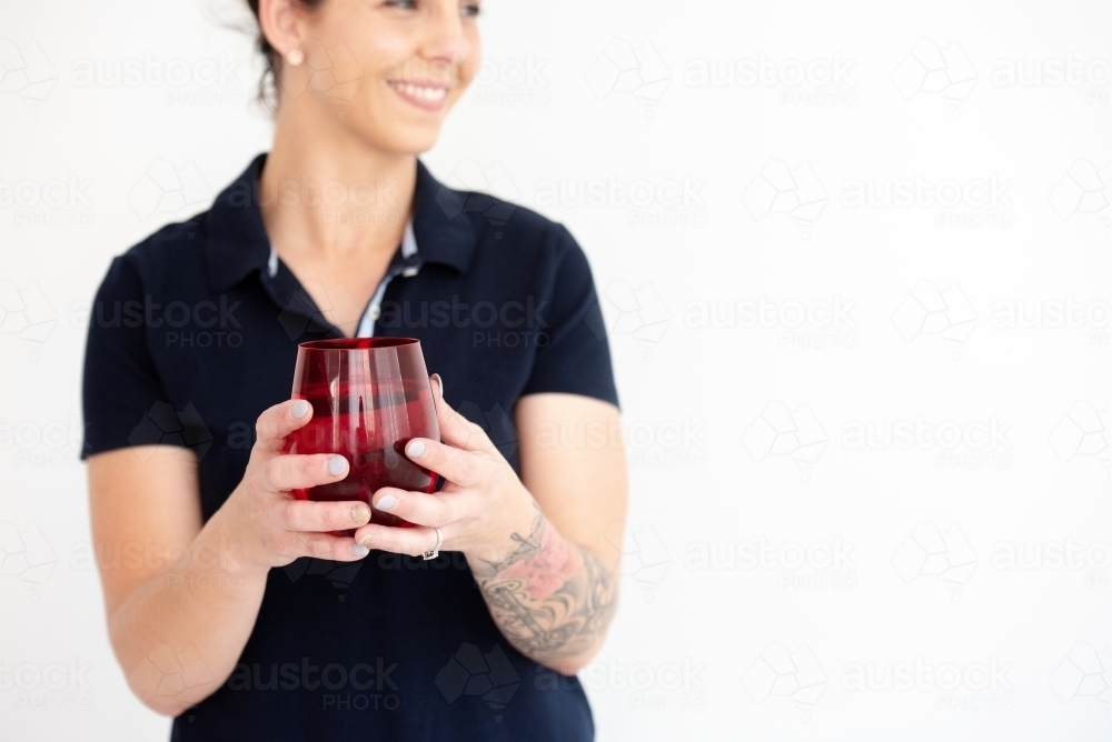 woman holding glass of water smiling looking right white background - Australian Stock Image