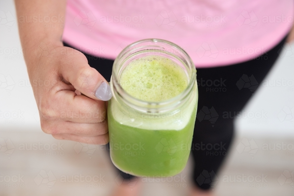 woman holding green juice close up workout clothes - Australian Stock Image