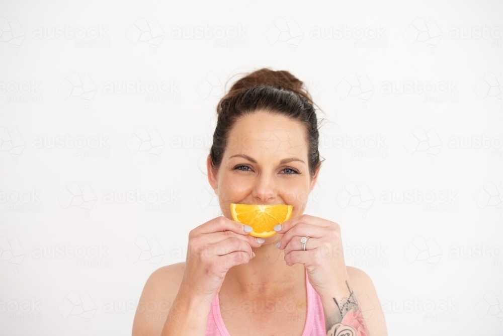 woman holding healthy snack orange slice on white background - Australian Stock Image
