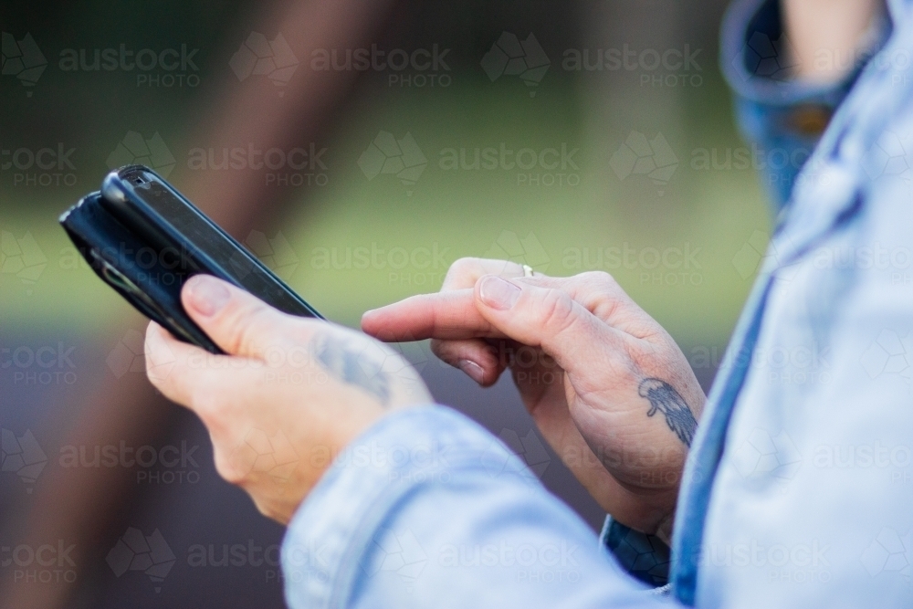 Woman holding phone using to fill in form - Australian Stock Image